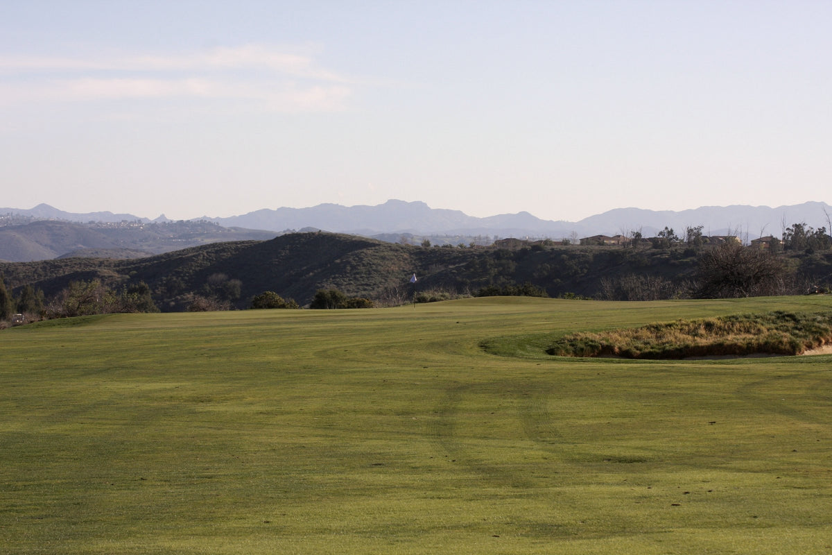A wide golf course fairway rolling toward distant hills
